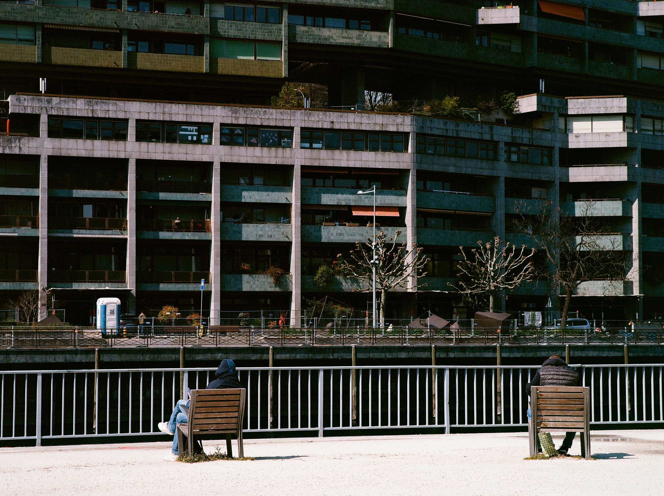Two men sitting with some social distancing on a individual public seats